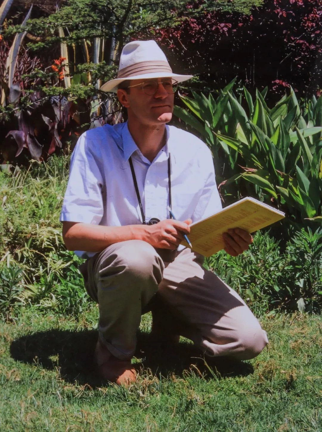 Norman Ward, kneeling observing nature with a sketchbook.